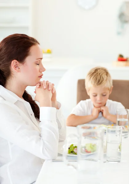 Сконцентрированные мать и сын молятся во время обеда — стоковое фото