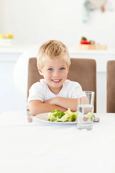 Симпатичный маленький мальчик, готовый съесть свой салат на обед, сидя за столом. — стоковое фото