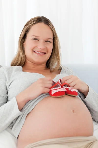 Εγκύου, βάζοντας τα παπούτσια μωρών την κοιλίτσα της — Φωτογραφία Αρχείου