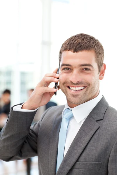 Homem de negócios hispânico feliz ao telefone enquanto sua equipe está trabalhando — Fotografia de Stock