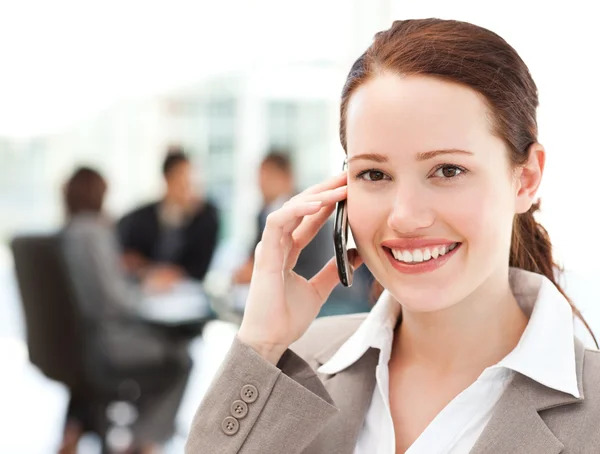 Aantrekkelijke zakenvrouw op de telefoon terwijl haar team werkt — Stockfoto
