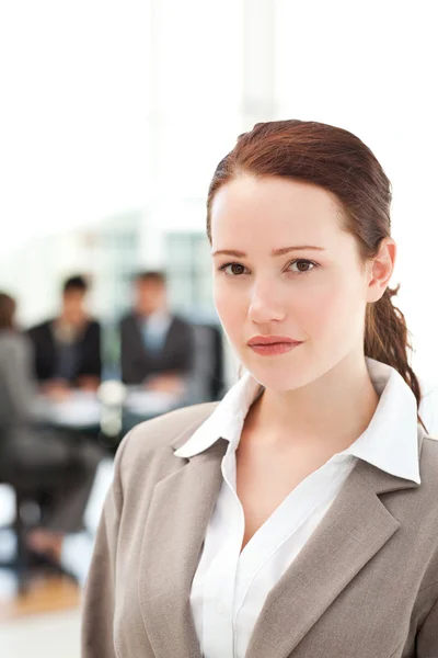 Серйозна бізнес-леді стоїть під час зустрічі зі своєю командою — стокове фото
