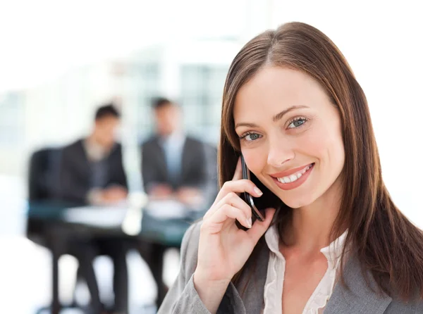 Mulher de negócios cativante ao telefone enquanto sua equipe está trabalhando — Fotografia de Stock