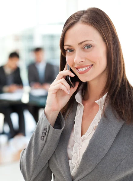 Zufriedene Geschäftsfrau telefoniert während ihr Team arbeitet — Stockfoto