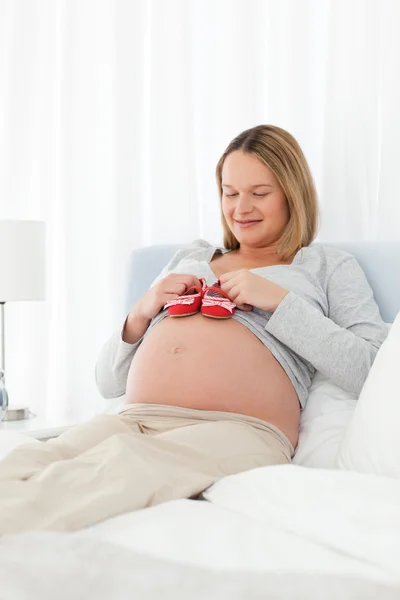 Mulher muito grávida ter sapatos de bebê em sua barriga descansando em — Fotografia de Stock