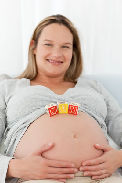Adorabile donna bionda con lettere mamma sulla pancia — Foto Stock