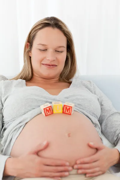 Linda mujer embarazada con letras de mamá en su vientre —  Fotos de Stock