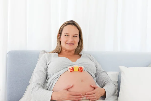 Ritratto di una donna incinta che ha lettere di mamma sulla pancia — Foto Stock