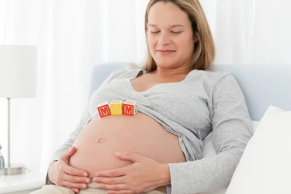 Femme détendue regardant les lettres de maman sur son ventre — Photo