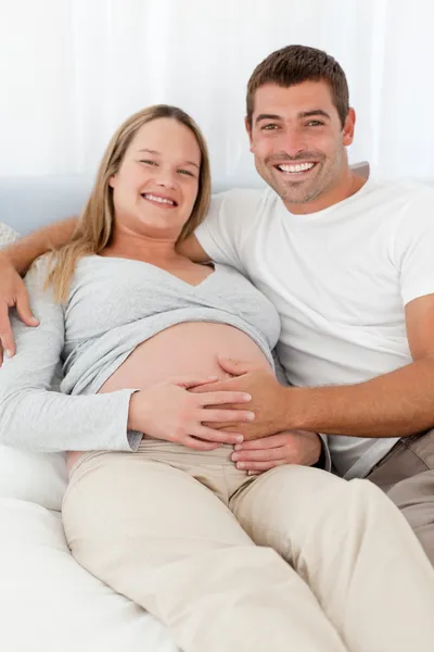 Happy future parents lying on a bed — Stock Photo, Image