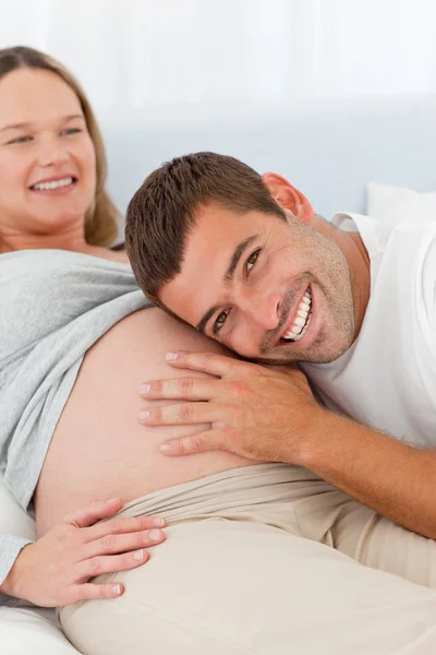 Счастливый мужчина слушает животы своей беременной жены — стоковое фото