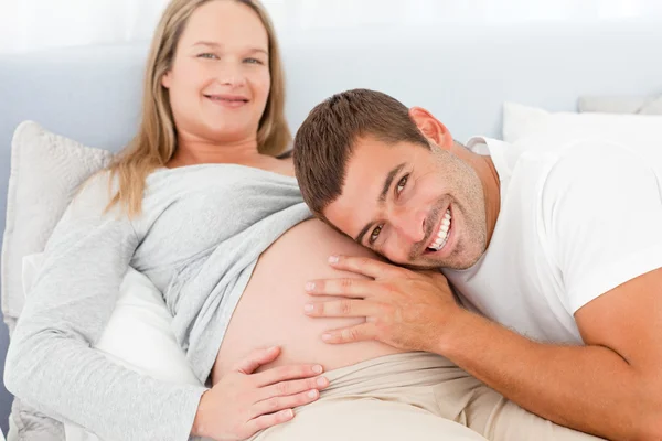 Retrato de un hombre escuchando el vientre de su esposa embarazada — Foto de Stock