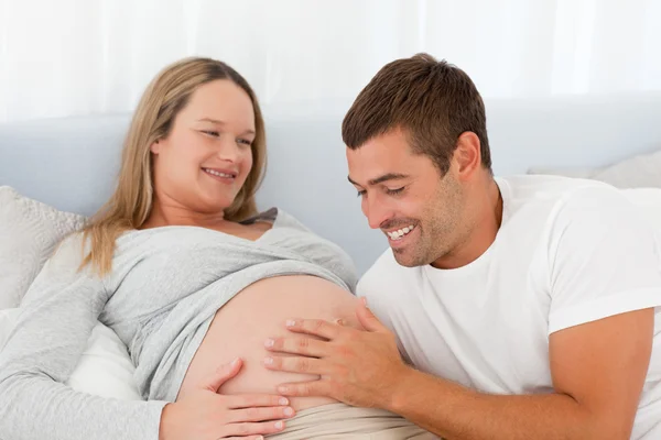 Feliz futuro papá tocando el vientre de su esposa mientras se relaja —  Fotos de Stock