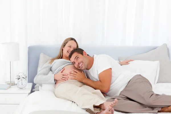 Lustiger Mann legt seinen Kopf auf den Bauch seiner schwangeren Frau — Stockfoto