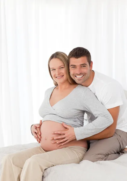 Mulher grávida bonito tocando sua barriga com seu marido no b — Fotografia de Stock