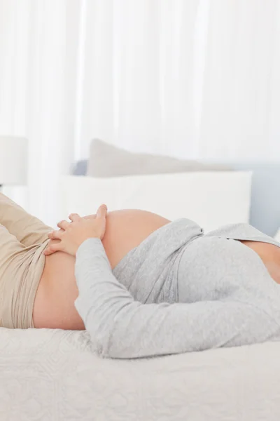 Close up of a future mother lying on the bed and touching her be — Stock Photo, Image