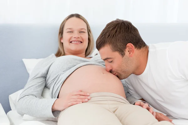 Happy man kissing the belly of his pregnant wife in the bed — Stock Photo, Image