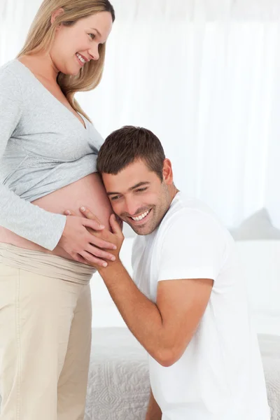 Glücklicher Mann im Knie, der auf den Bauch seiner schwangeren Frau hört — Stockfoto