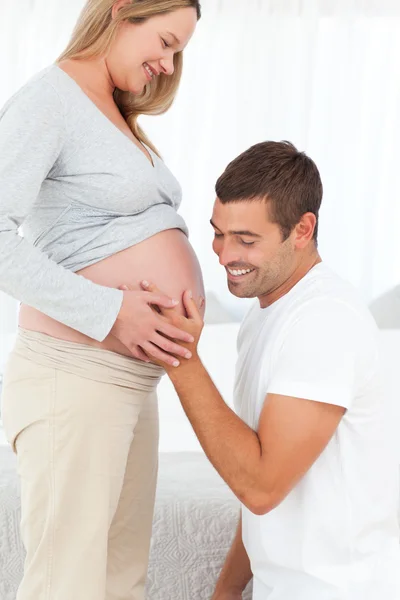 Homme heureux dans le genou sentant le ventre de sa femme enceinte — Photo