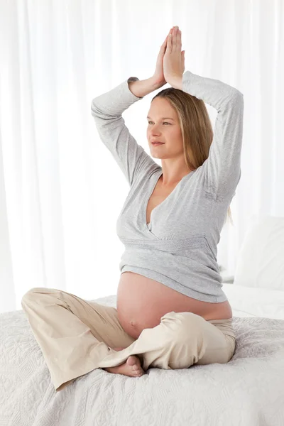 Side view of a future mom doing medidation on a bed — Stock Photo, Image