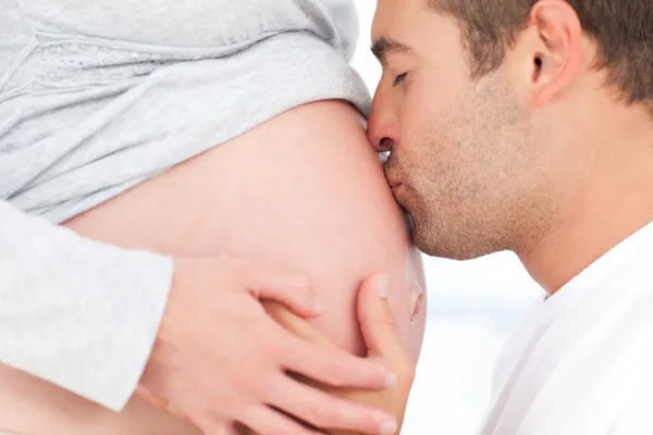 Close up de um homem beijando a barriga de sua linda esposa grávida — Fotografia de Stock