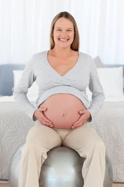 Visão frontal de uma futura mãe feliz sentada em uma bola de fitness — Fotografia de Stock