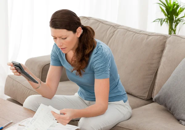 Donna nervosa guardando i suoi debiti finanziari nel soggiorno — Foto Stock