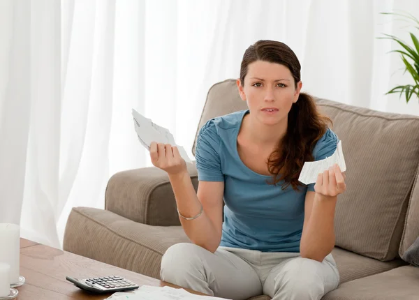 Mujer seria sosteniendo facturas mientras hace sus cuentas en el livi —  Fotos de Stock