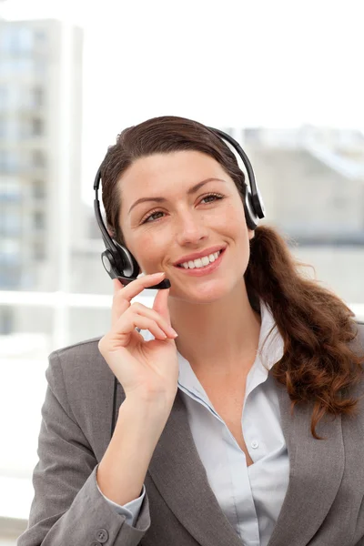 Vrolijke zakenvrouw met behulp van de luidspreker zit op haar Bureau — Stockfoto