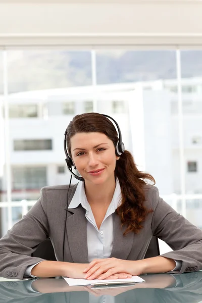 Bonita mulher de negócios ao telefone com fone de ouvido sentado em uma mesa — Fotografia de Stock
