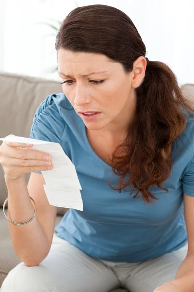 Νευρικό γυναίκα κοιτάζοντας ένα νομοσχέδιο, ενώ κάνει οι λογαριασμοί της — Φωτογραφία Αρχείου