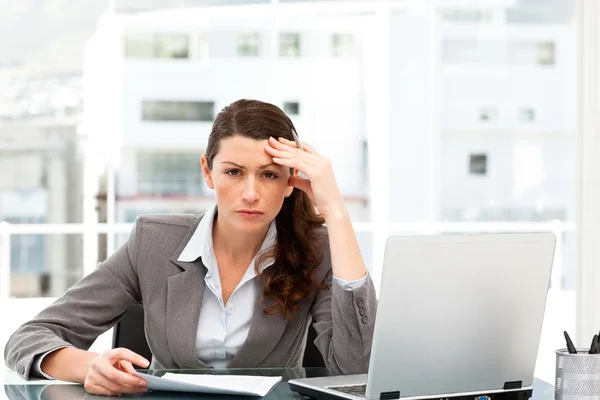 Femme d'affaires inquiète travaillant à son bureau avec ordinateur portable et dossier — Photo