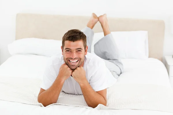 Bonito homem rindo deitado em sua cama — Fotografia de Stock