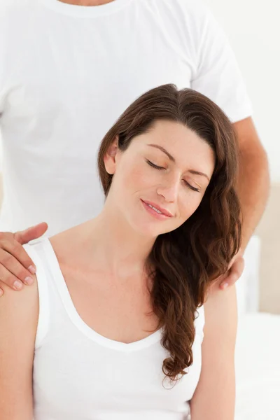 Attentive man massaging his girlfriend's back sitting on their b — Stock Photo, Image