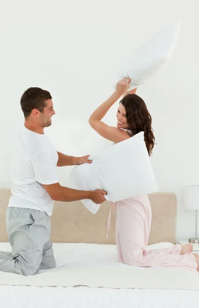 Lovely couple doing a pillow fight on their bed — Stock Photo, Image