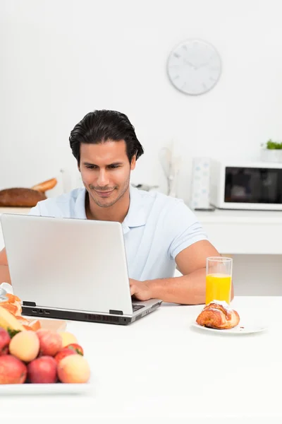 Carismatico uomo ispanico che lavora sul suo computer portatile in cucina — Foto Stock
