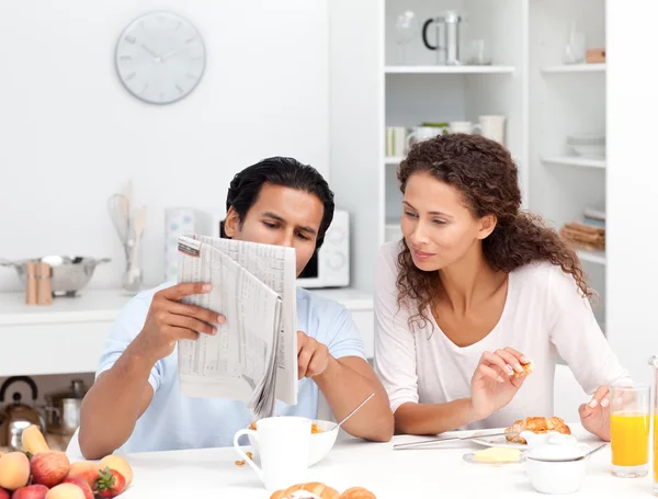 Счастливая пара читает газету вместе за завтраком — стоковое фото