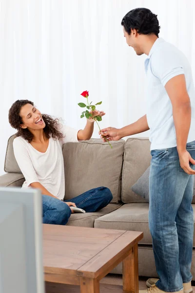 Entzückender Mann gibt seiner schönen Freundin im Livin eine Rose — Stockfoto