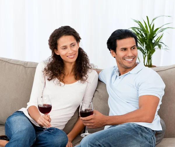Encantador casal beber vinho tinto sentado no sofá — Fotografia de Stock