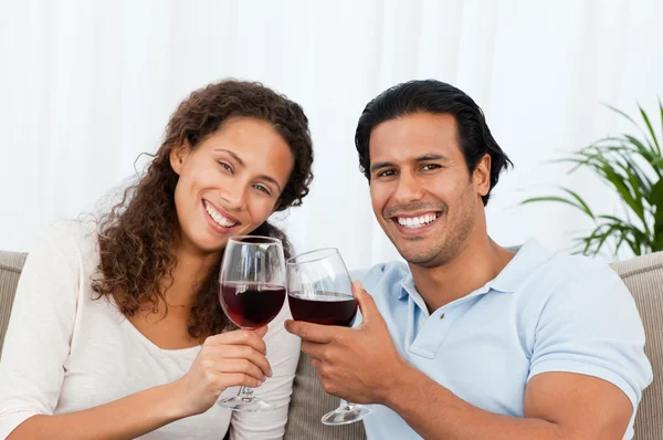 Счастливая пара пьет красное вино сидя на диване — стоковое фото