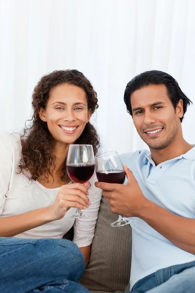 Casal feliz clinking copos de vinho tinto no sofá — Fotografia de Stock