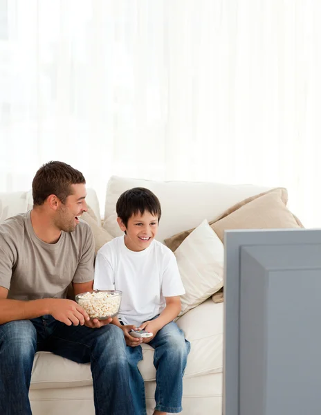 Happy boy watching television with his father on the sofa — Stock Photo, Image
