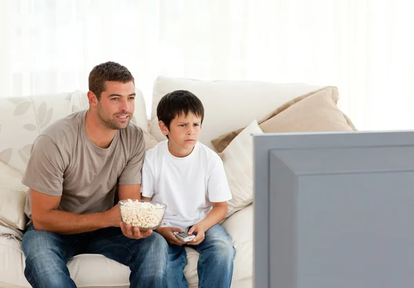 集中的父亲和儿子边看电视边吃流行音乐 — 图库照片