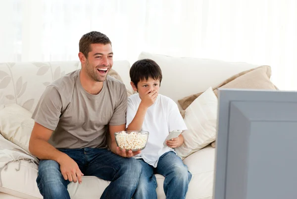 快乐的人和他的儿子坐在沙发上看电视 — 图库照片