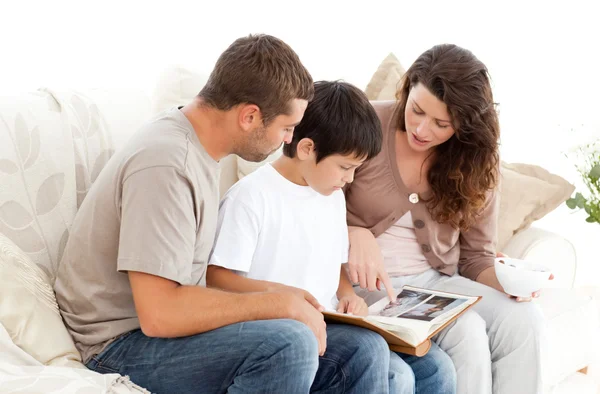 Glückliche Familie beim gemeinsamen Betrachten eines Fotoalbums auf dem Sofa — Stockfoto