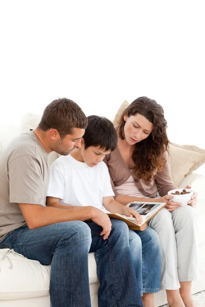Adorable family looking at a photo album together on the sofa — Stock Photo, Image