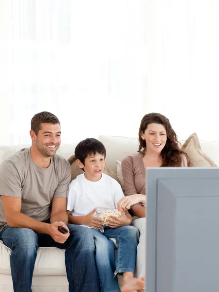 Счастливая семья смотрит телевизор, поедая попкорн вместе — стоковое фото