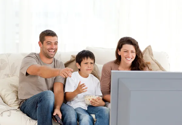 Família rindo enquanto assistem televisão juntos — Fotografia de Stock