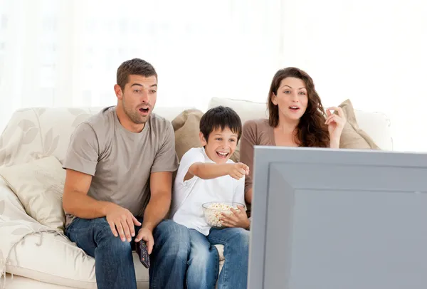 Familia feliz viendo una película en la televisión juntos en el sofá —  Fotos de Stock
