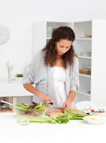 Mulher bonita cortando legumes enquanto prepara uma salada — Fotografia de Stock